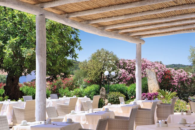 La Rocca Sardinia outdoor dining restaurant surrounded by trees flowering bushes