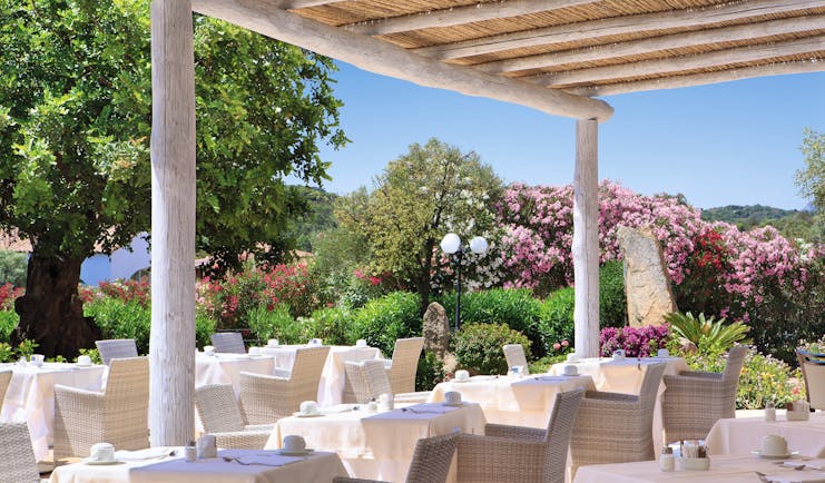 La Rocca Sardinia outdoor dining restaurant surrounded by trees flowering bushes
