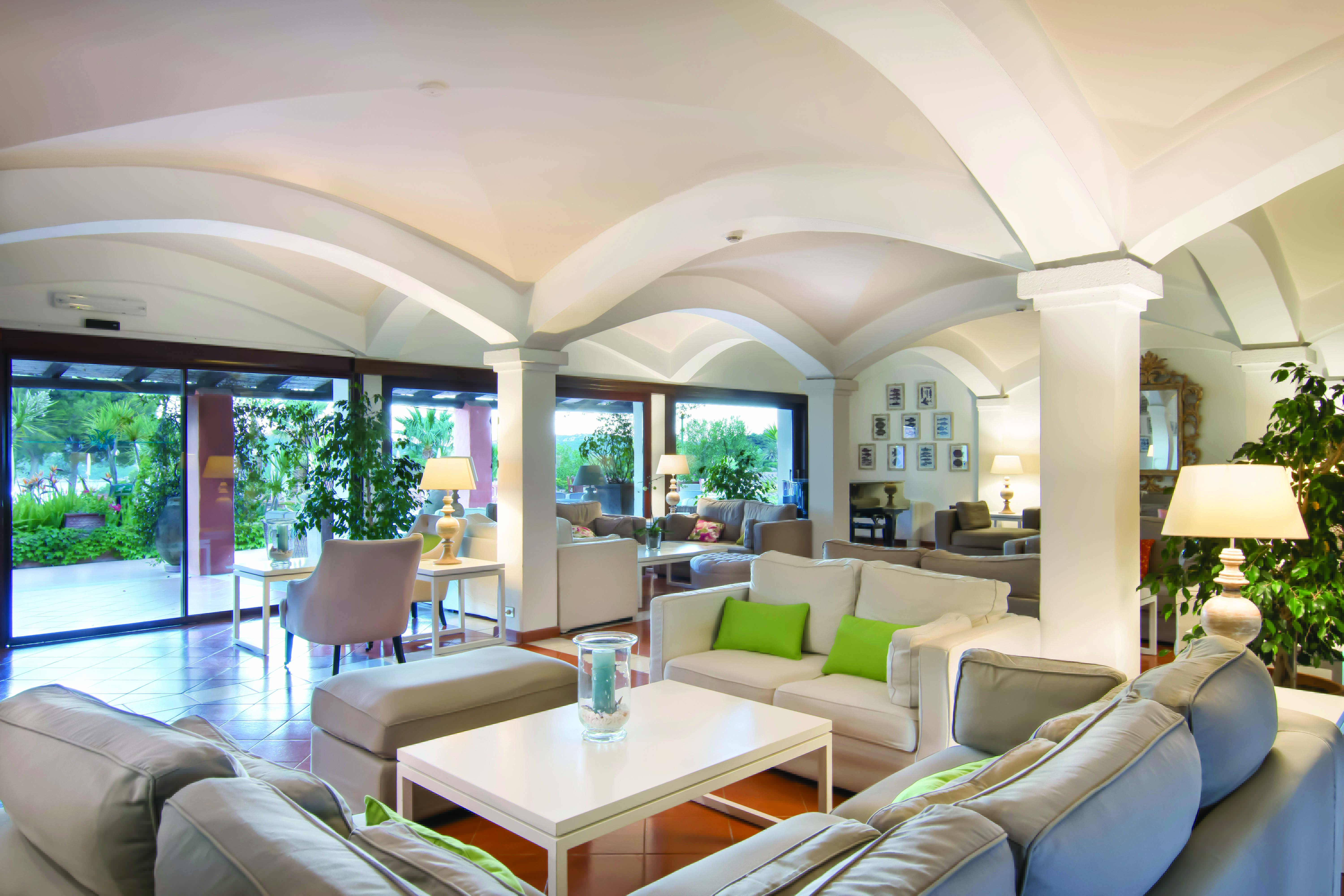 Hotel Le Ginestre Sardinia lounge, communal seating area, large white sofas, french windows opening onto garden, bright elegant decor