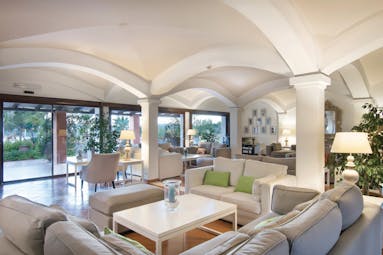 Hotel Le Ginestre Sardinia lounge, communal seating area, large white sofas, french windows opening onto garden, bright elegant decor