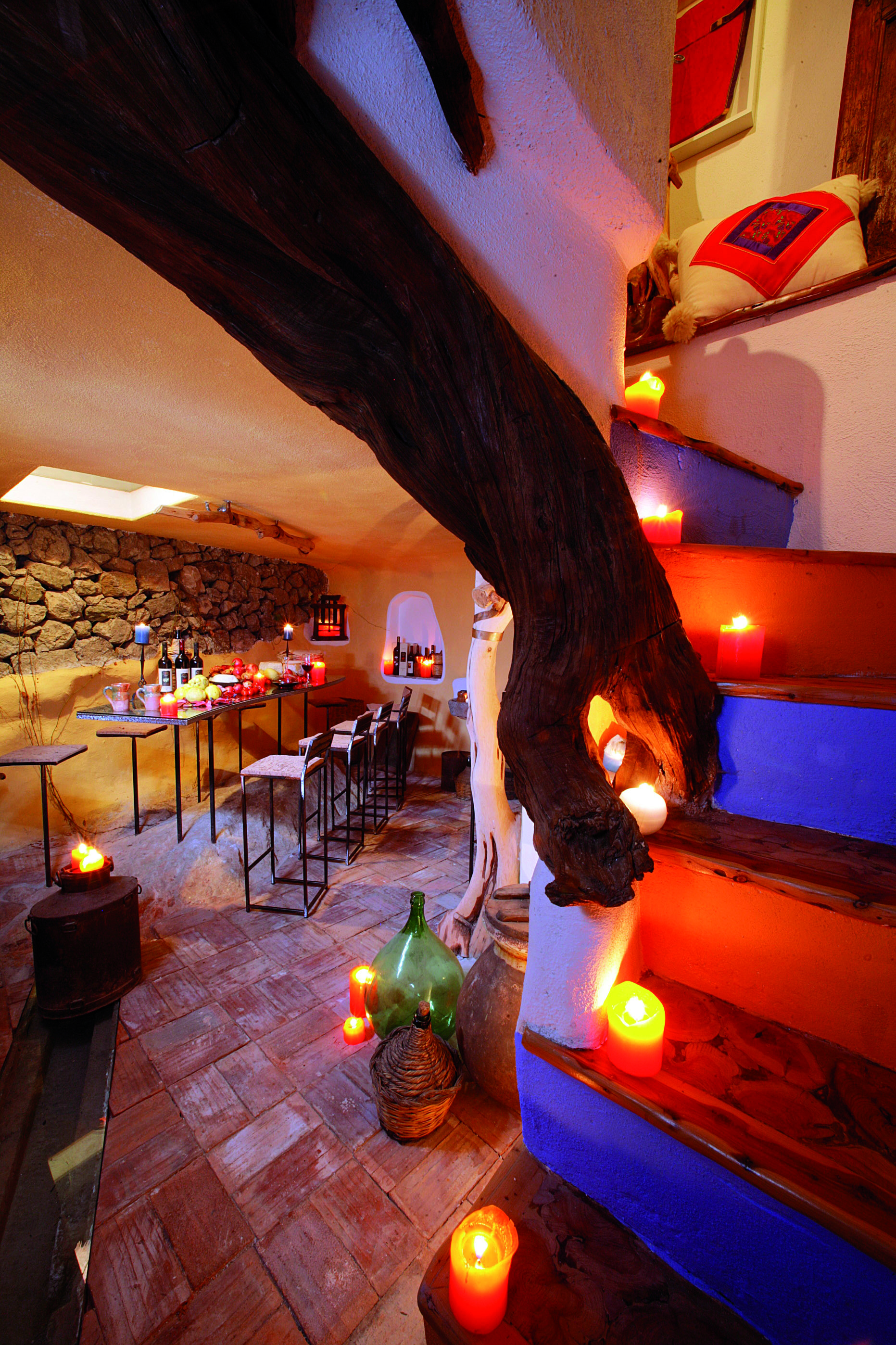 Hotel Su Gologone candle lit dining area with wooden tables and stools set up around the room 