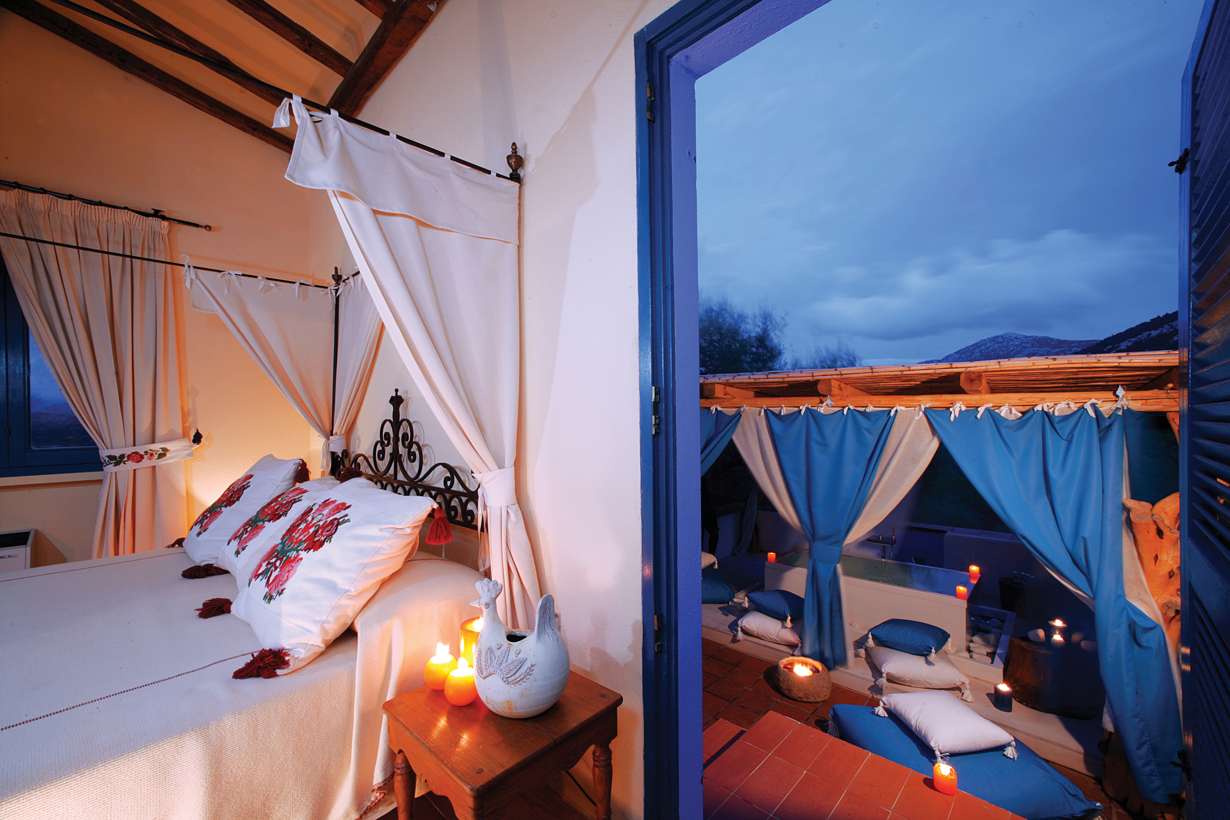 Junior suite with white bed with drapes and doors opening onto outside 