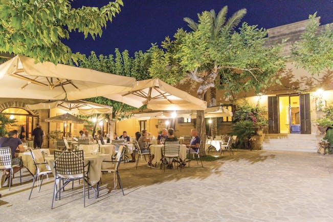 Baglio Oneto restaurant terrace, outdoor dining patio, tables and chairs, umbrellas, trees