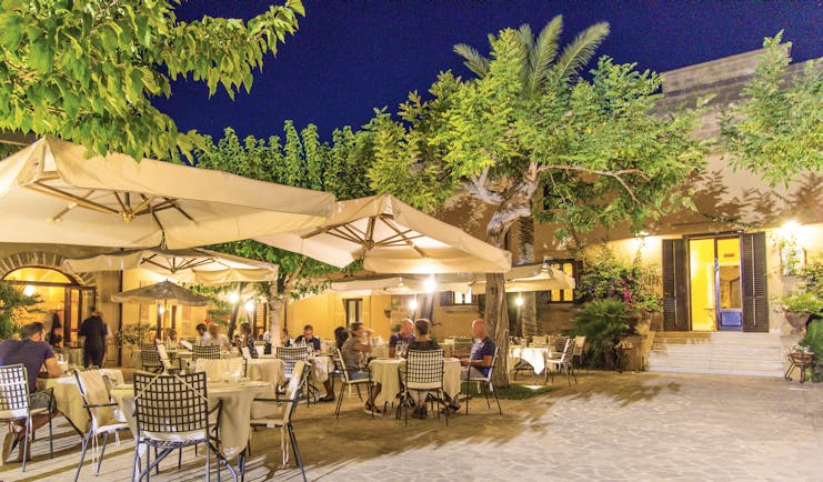 Baglio Oneto restaurant terrace, outdoor dining patio, tables and chairs, umbrellas, trees