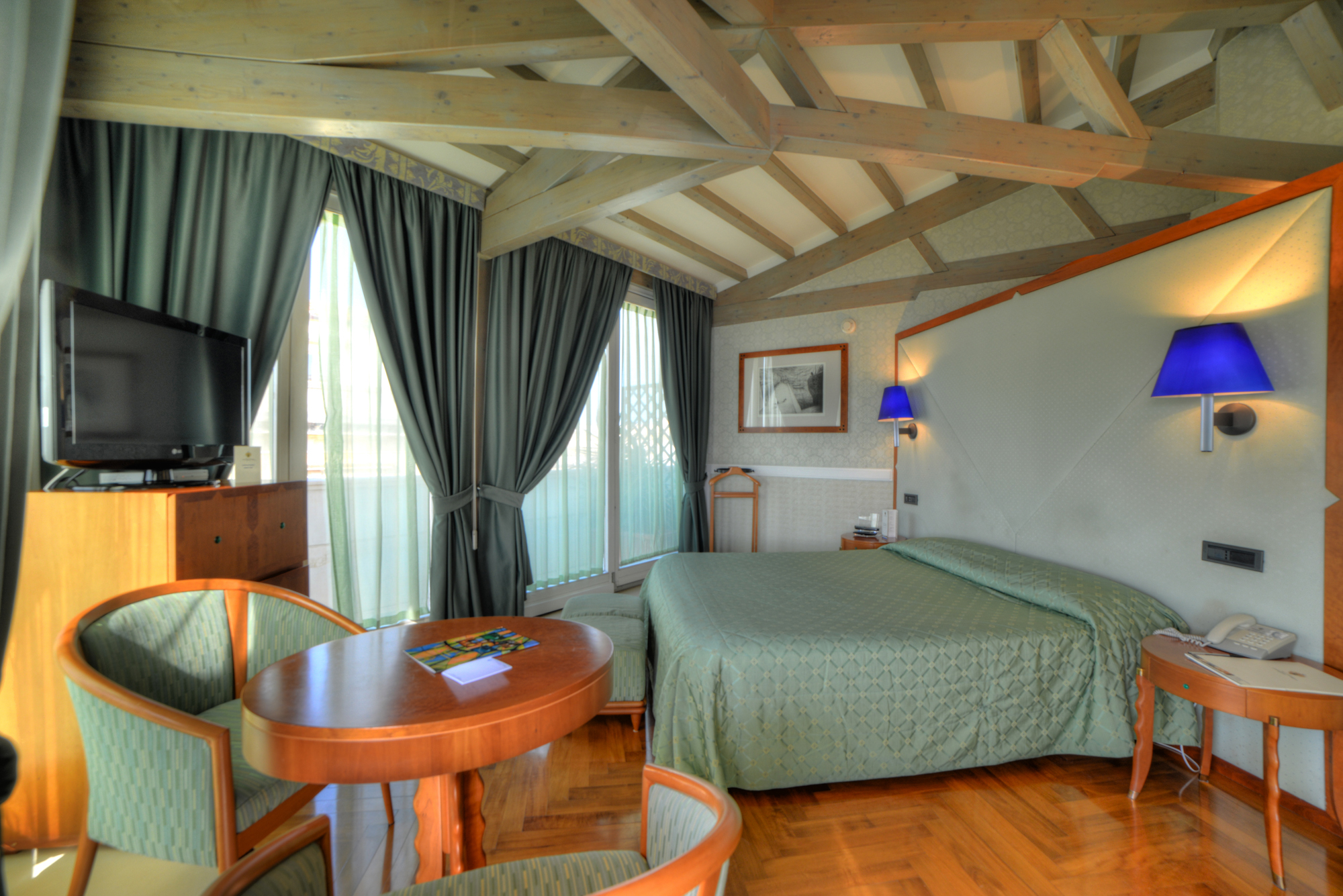 Superior sea view room with green and blue colour scheme, double bed, television and view over the sea
