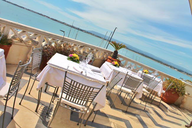 Dining area on the terrace looking over the sea with tables and chairs set up for dining 