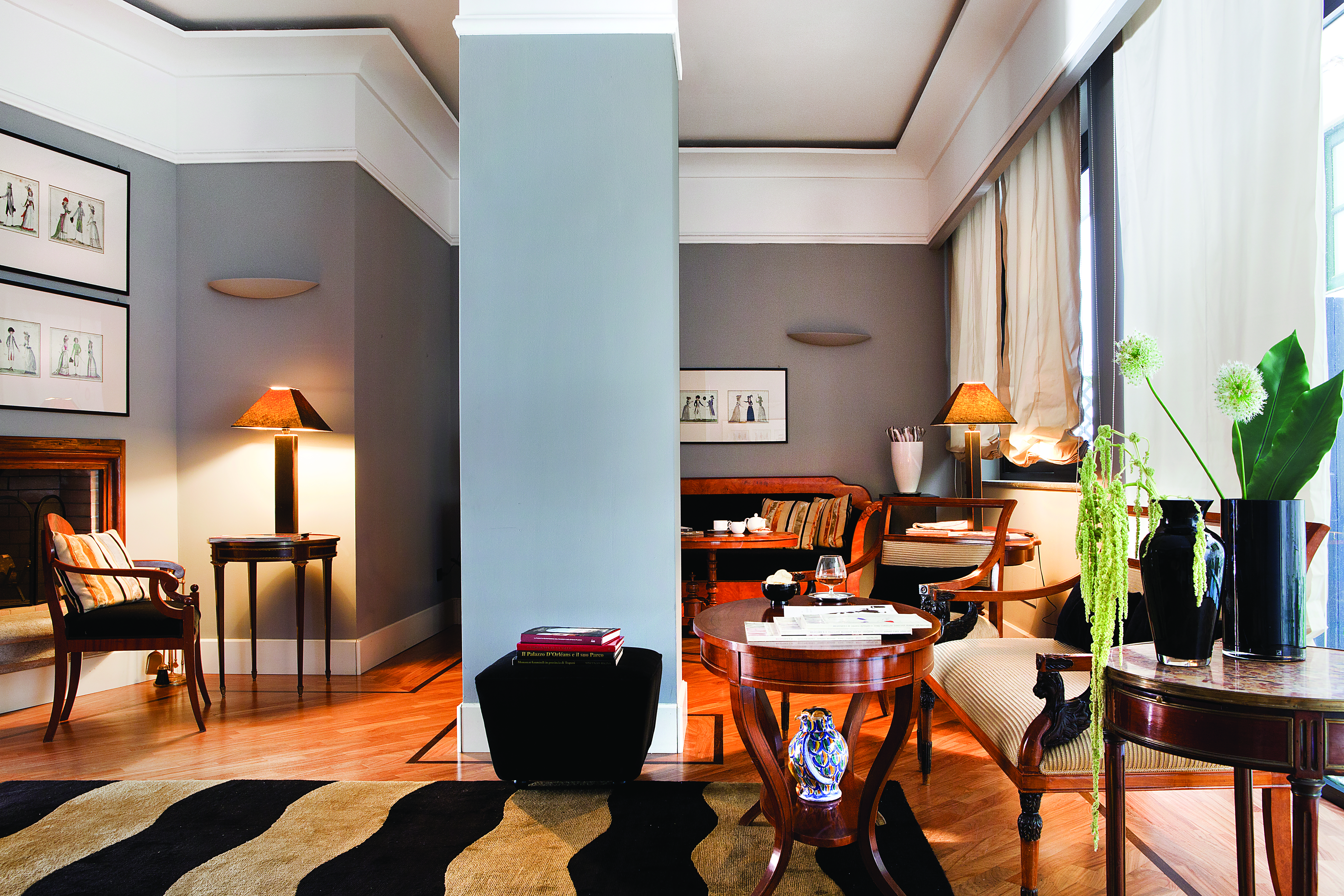 Lounge at the Hotel Plaza Opera with grey walls, wooden tables and chairs and painting on the walls