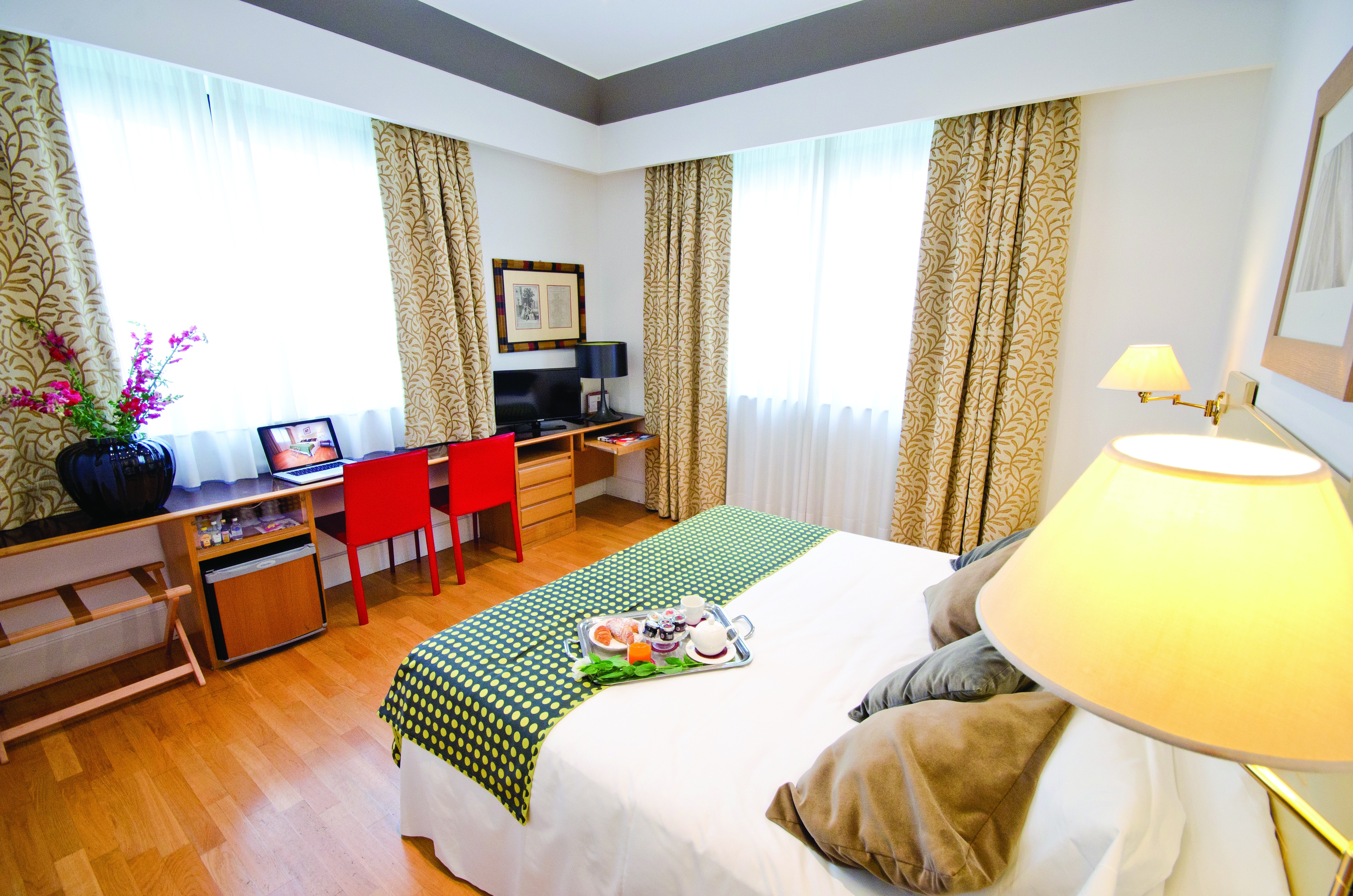 standard double room at the Hotel Plaza Opera, with a green colour scheme, including a double bed, desk and television