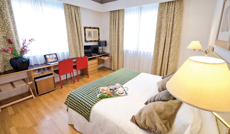 standard double room at the Hotel Plaza Opera, with a green colour scheme, including a double bed, desk and television