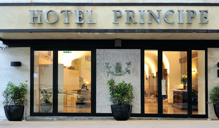 Hotel Principe di Villafranca entrance, hotel name, glass doors, lit up lobby