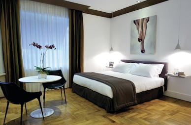 Hotel Principe di Villafranca junior suite, double bed, tables and chairs, wooden floor, bright modern decor