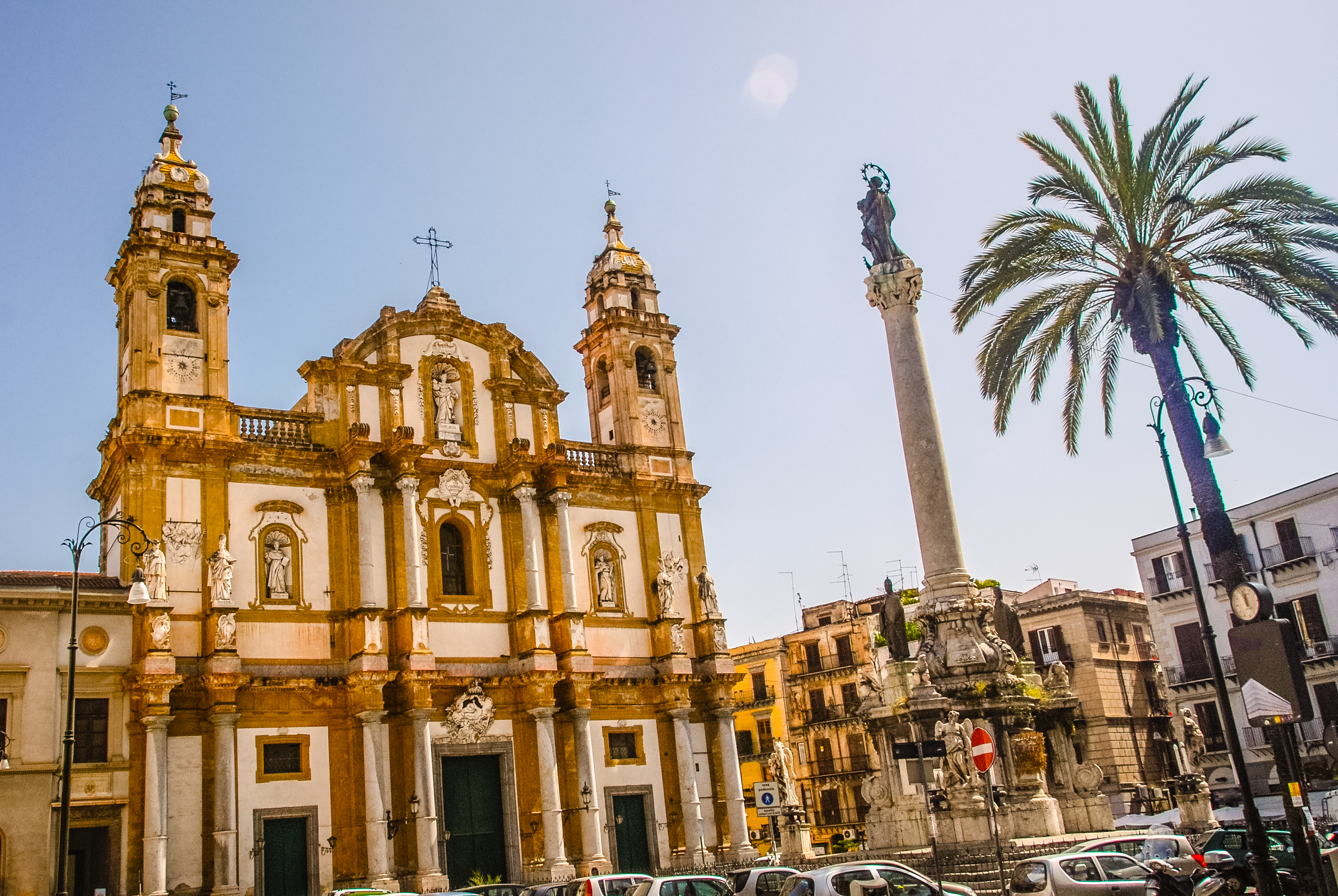 Baroque church with two towers next to palm tree in Palermo Sicily