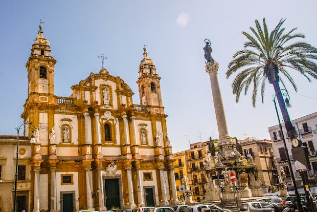 Baroque church with two towers next to palm tree in Palermo Sicily