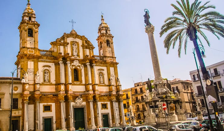 Baroque church with two towers next to palm tree in Palermo Sicily