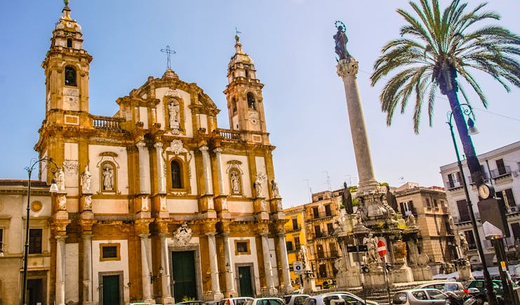 Baroque church with two towers next to palm tree in Palermo Sicily