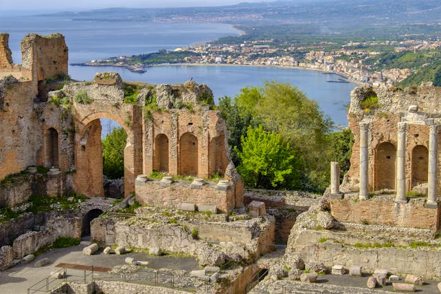 Columns and arches of the Greek theatre in taormina with sea behind