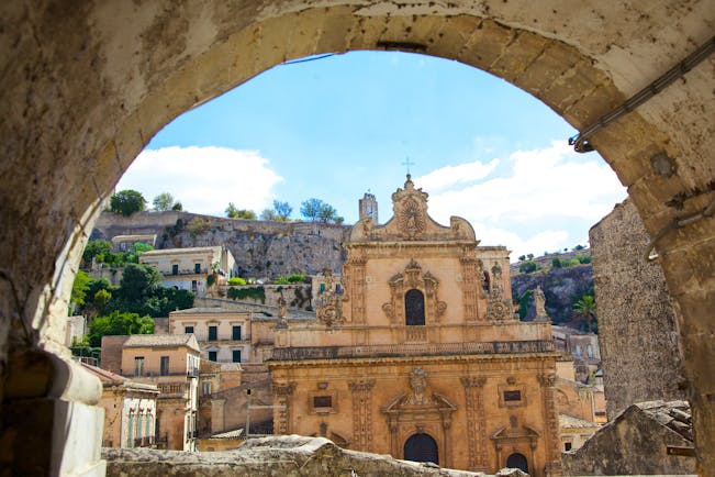 Baroque front of the cathedral of St Peter through a stone arch in Modica Sicily