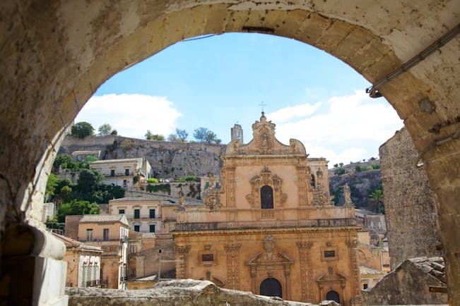 Baroque front of the cathedral of St Peter through a stone arch in Modica Sicily