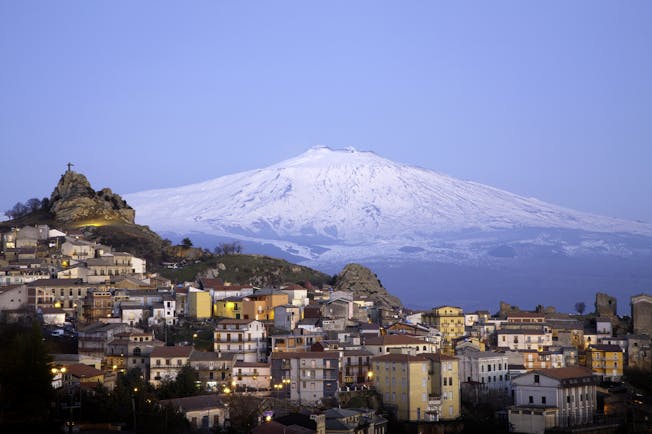 Snow capped Mount Etna with hilltop village of San Teodoro