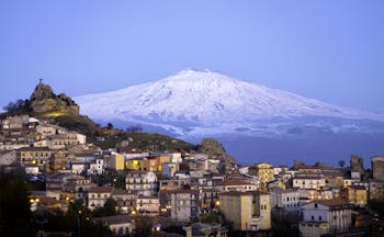 Snow capped Mount Etna with hilltop village of San Teodoro