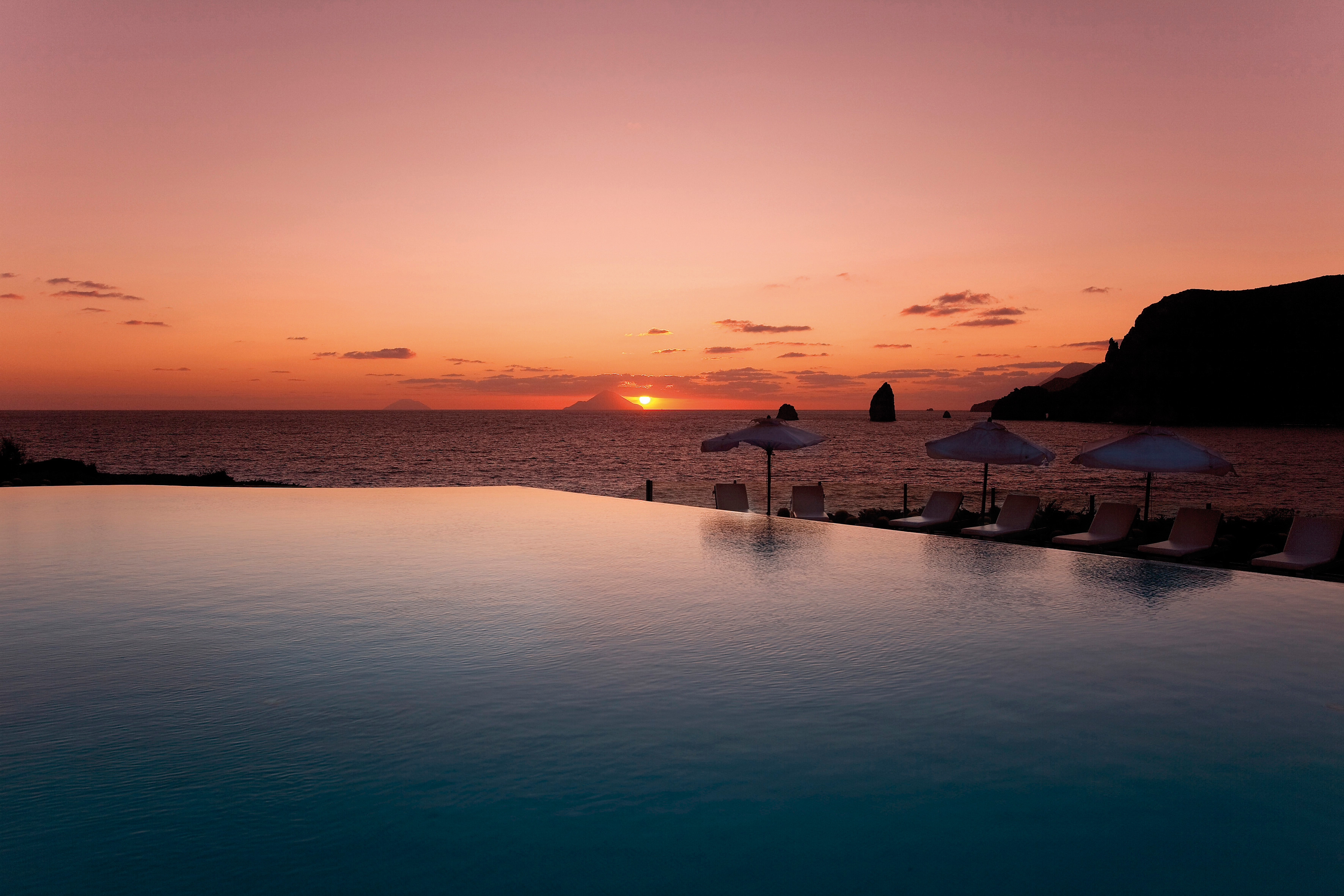 Pool sunset view with sun setting by the sea