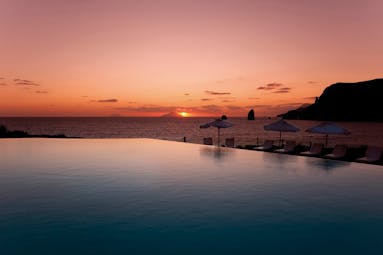Pool sunset view with sun setting by the sea