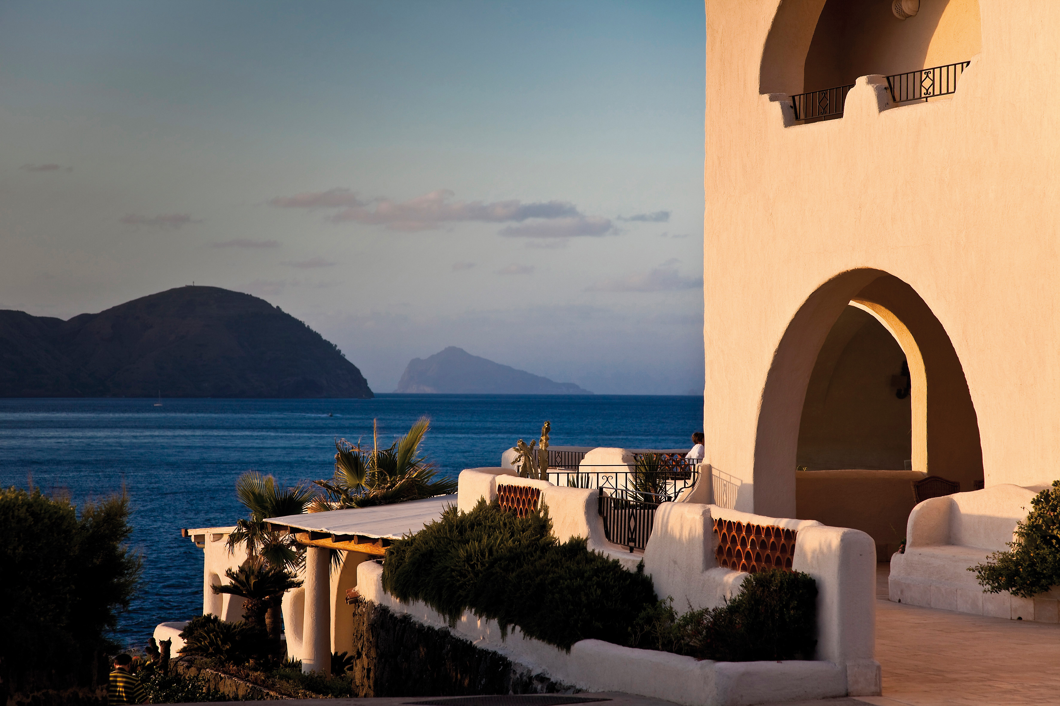 Outdoors terrace area with seats overlooking mountains and the sea