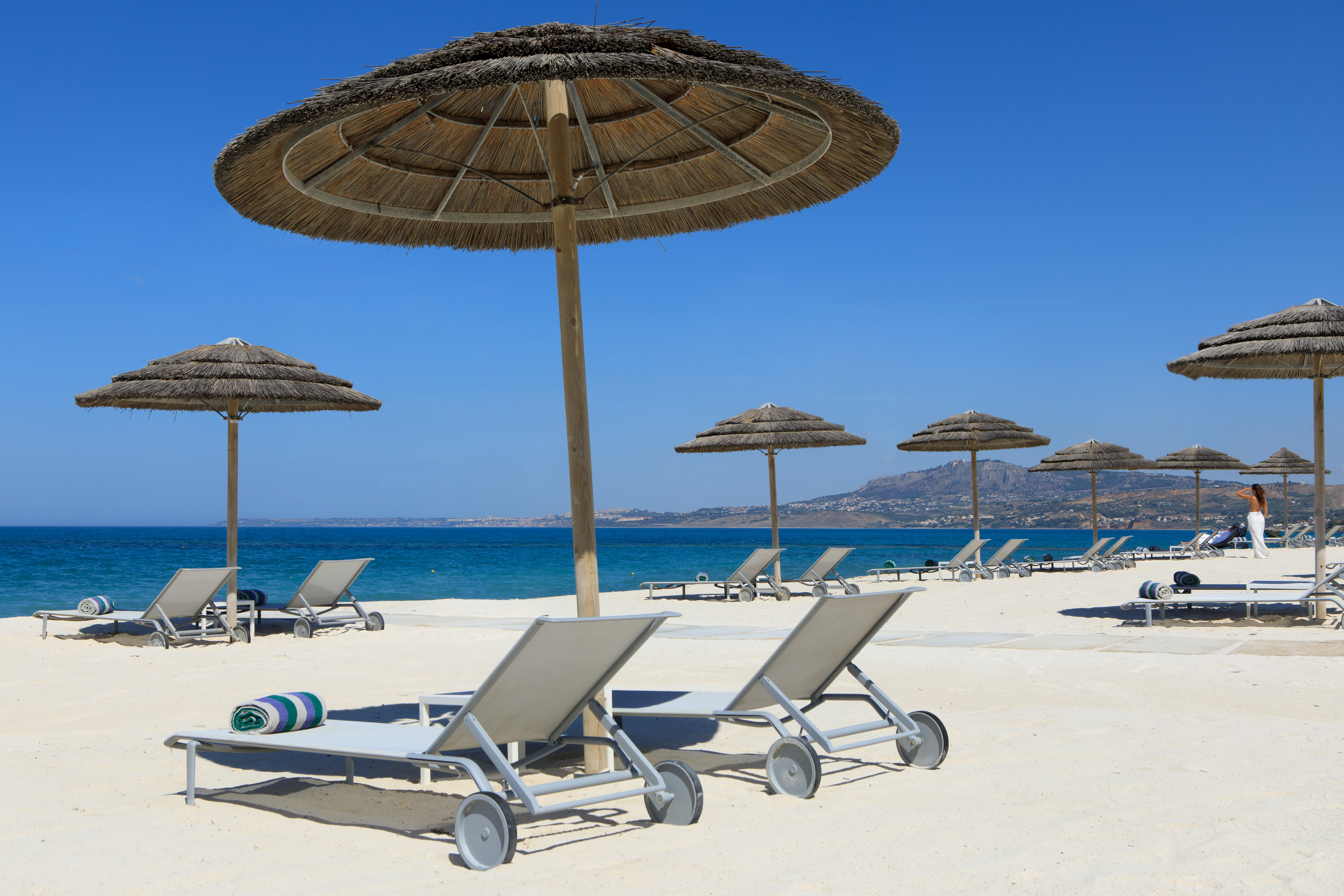 Verdura Resort white sand beach with sun beds and umbrellas