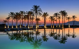 Verdura Resort evening with palm trees and swimming pool reflections