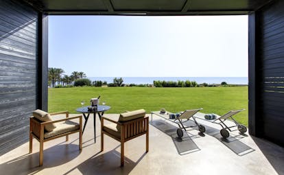 Verdura Resort room with chairs and sunloungers overlooking grass and sea