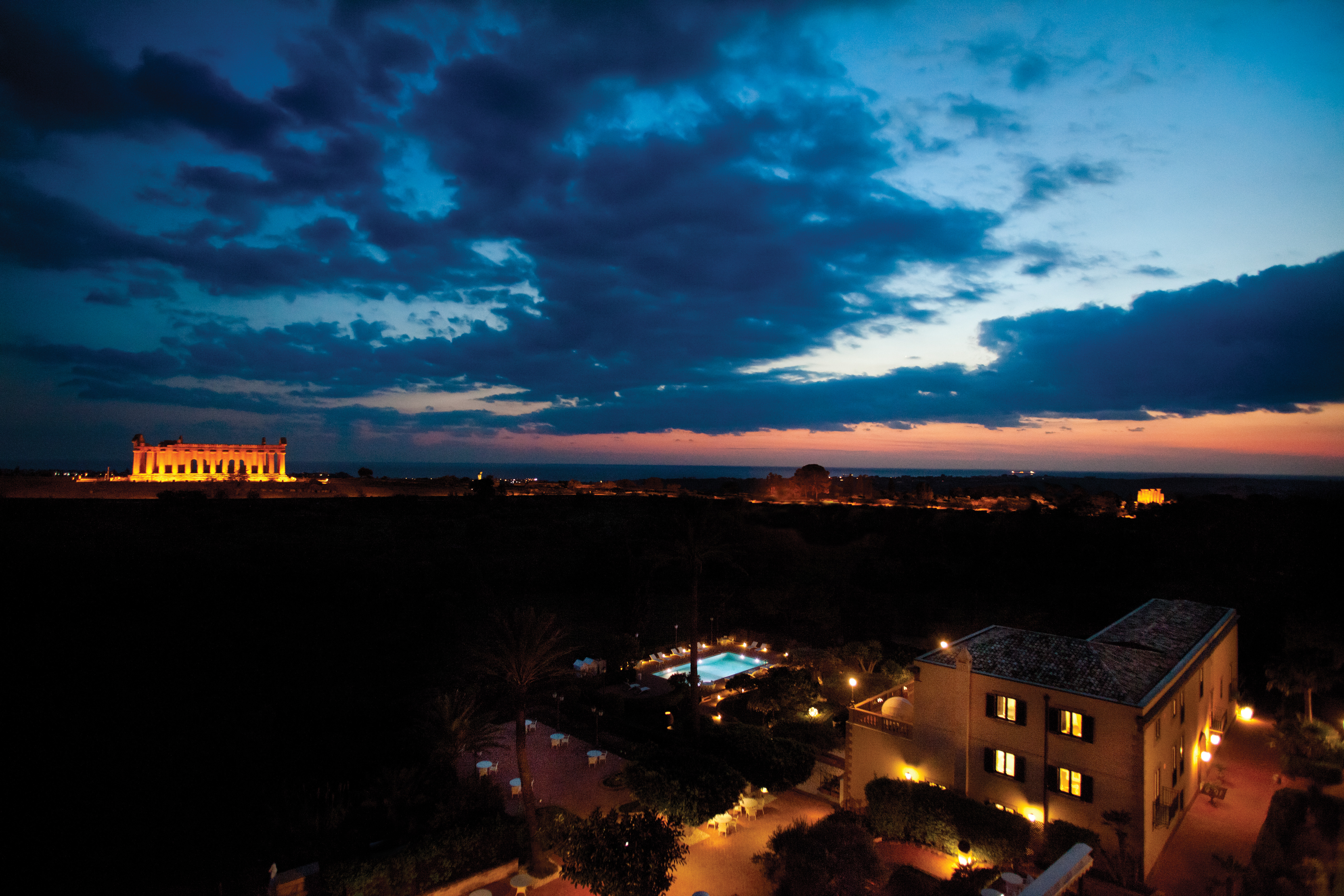 View from the hotel at night with a view of the temple of Athena lit up orange in the dark  