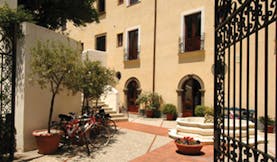 Villa Meligunis Sicily entrance iron gates patio bicycles potted plants hotel building