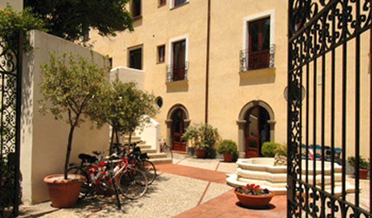Villa Meligunis Sicily entrance iron gates patio bicycles potted plants hotel building