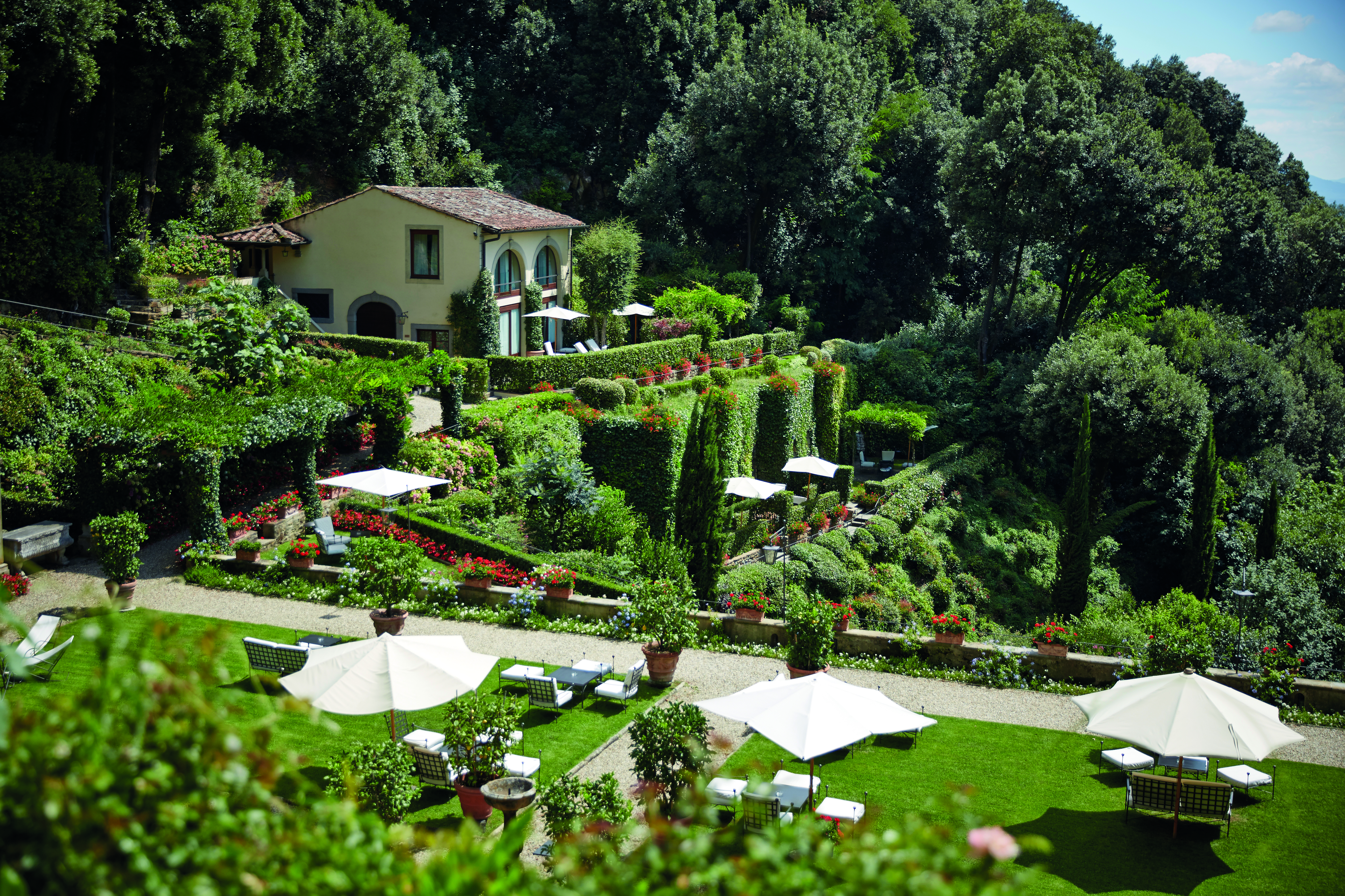 Villa San Michele Tuscany scenery  hotel on hillside lawns with sun loungers and umbrellas