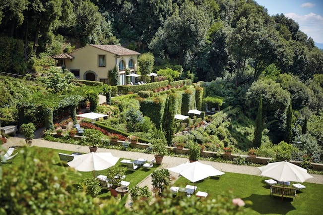 Villa San Michele Tuscany scenery  hotel on hillside lawns with sun loungers and umbrellas