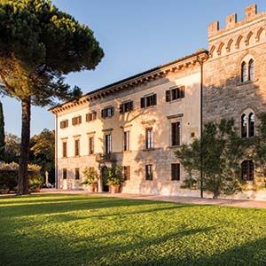 Borgo Pignano exterior of hotel building shown with lawn in front and vines growing up building 