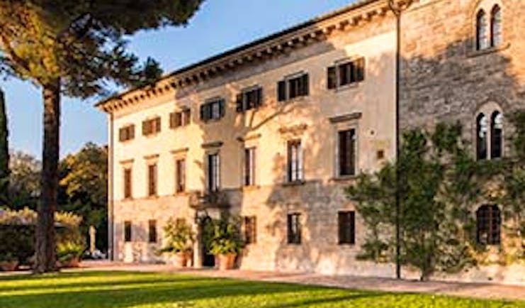Borgo Pignano exterior of hotel building shown with lawn in front and vines growing up building 