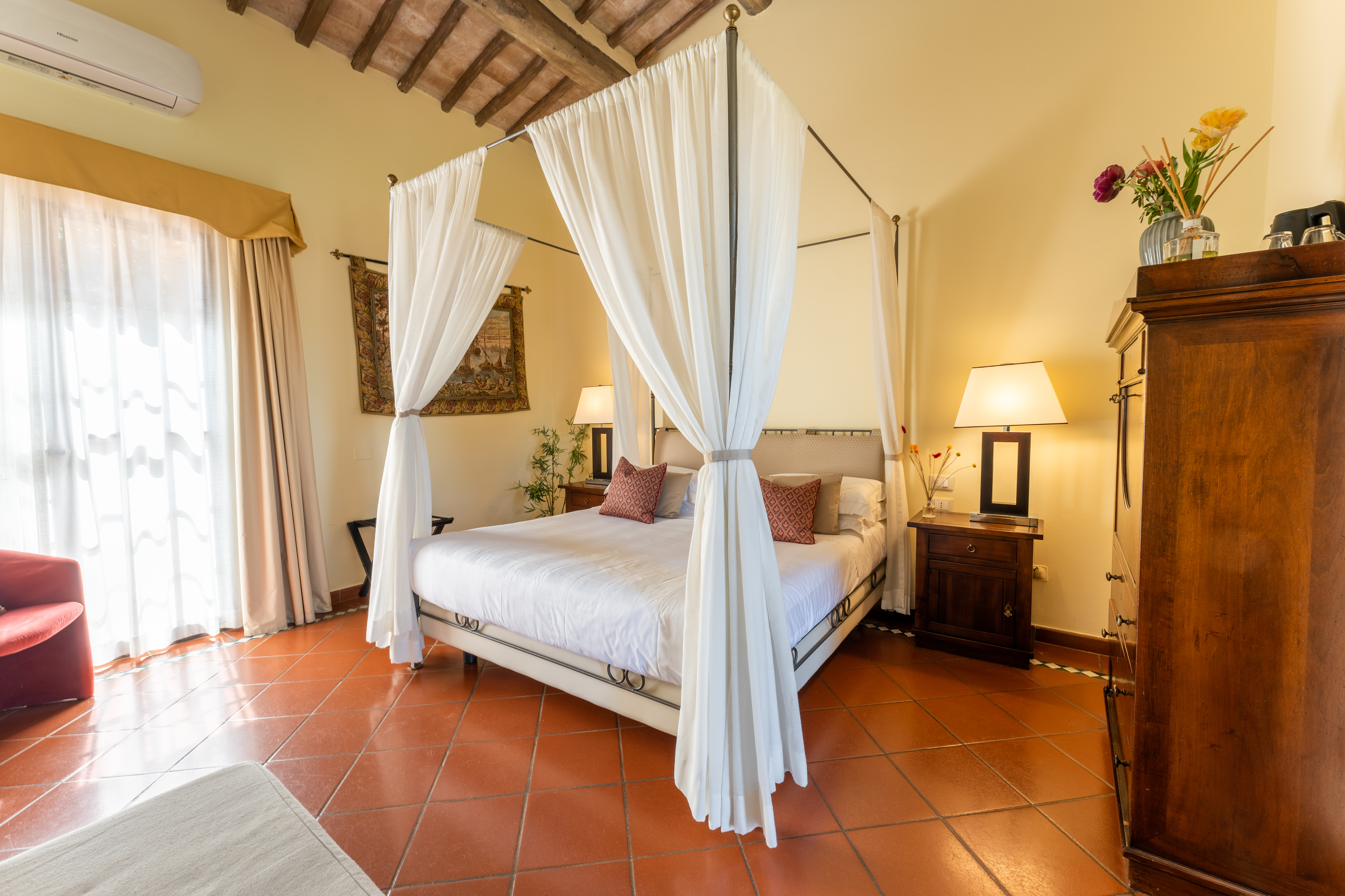 Borgo San Luigi Classic Terrace Room with canopy bed, terracotta tiled floor, high beamed ceiling, and dark wood furnishings