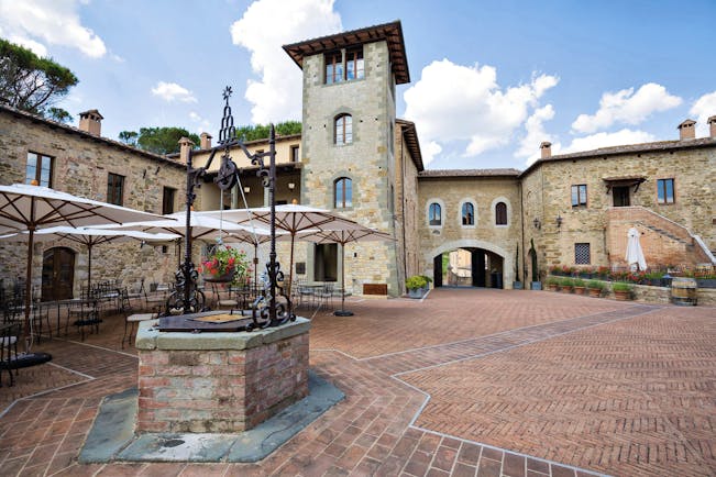 Castel Monastero Tuscany courtyard outdoor seating area surrounded by buildings