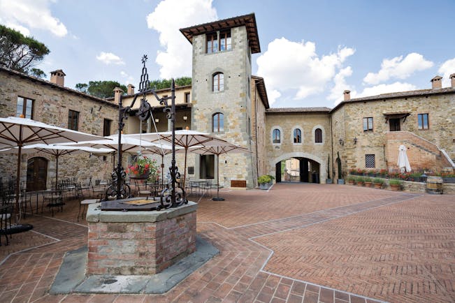 Castel Monastero Tuscany courtyard outdoor seating area surrounded by buildings