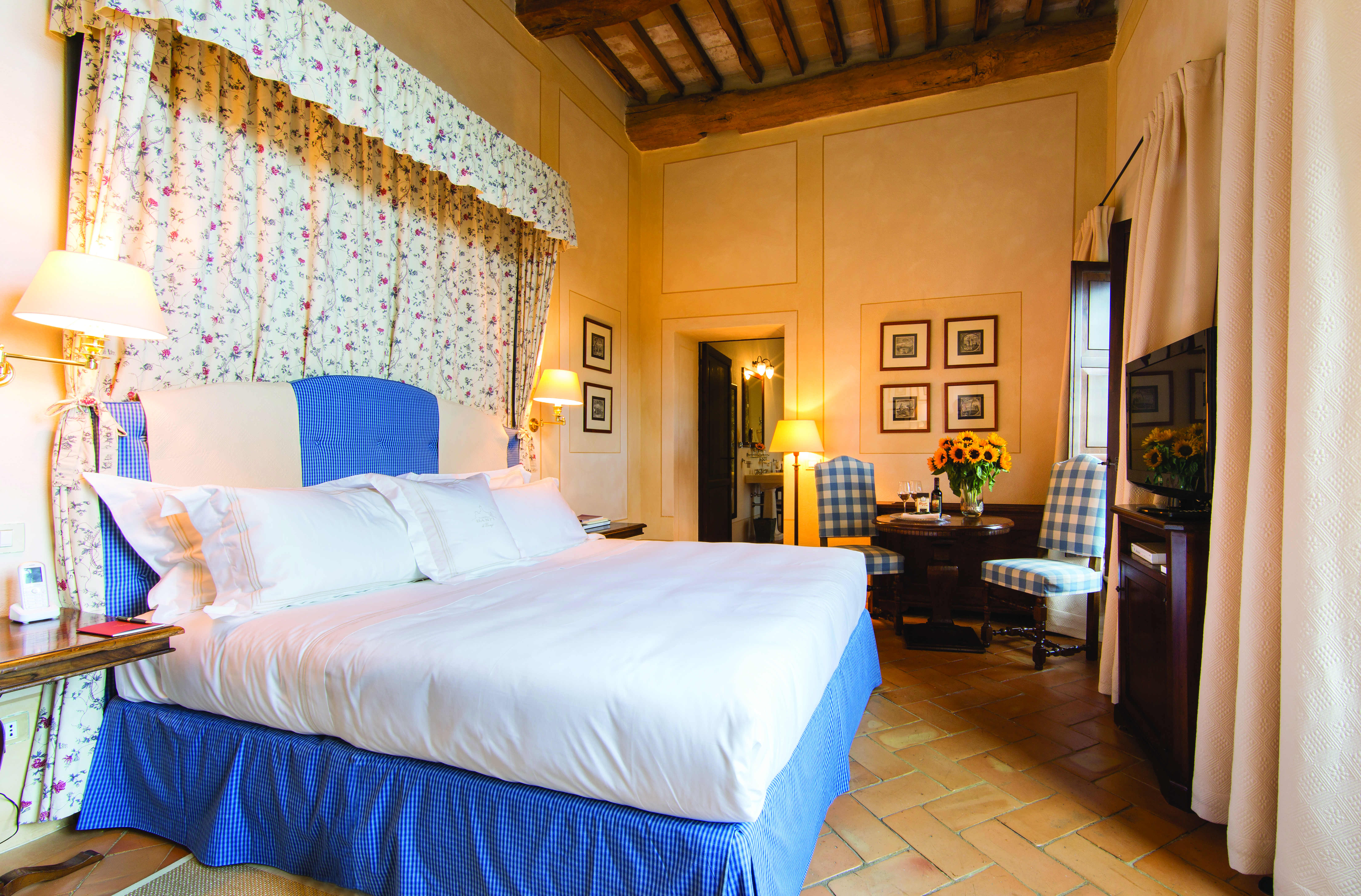 Classic room with large bed, purple and cream colour scheme, television and paintings hanging on the wall