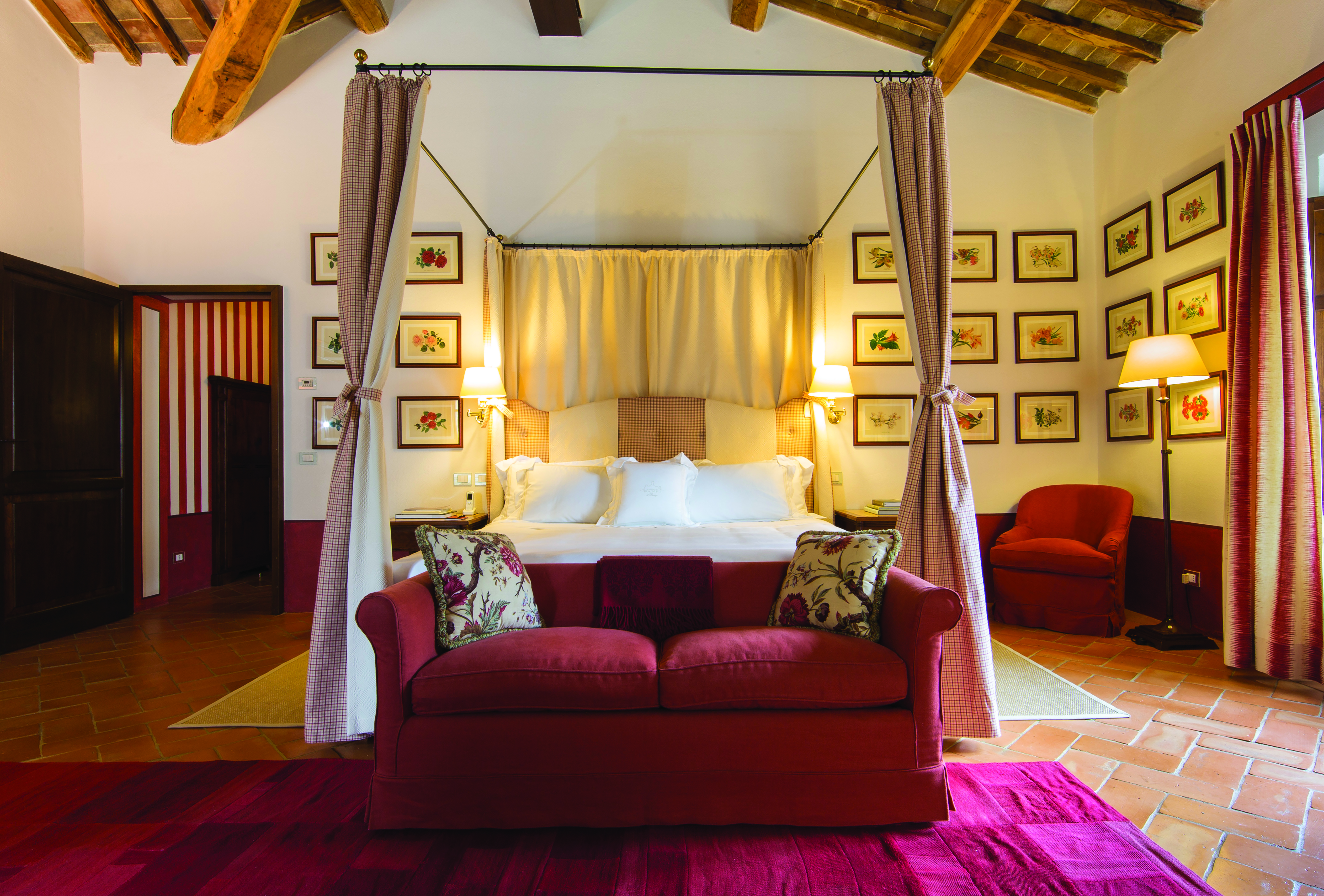 Double room with a large double bed, a pink colour scheme, sofa, and paintings hanging on the walls