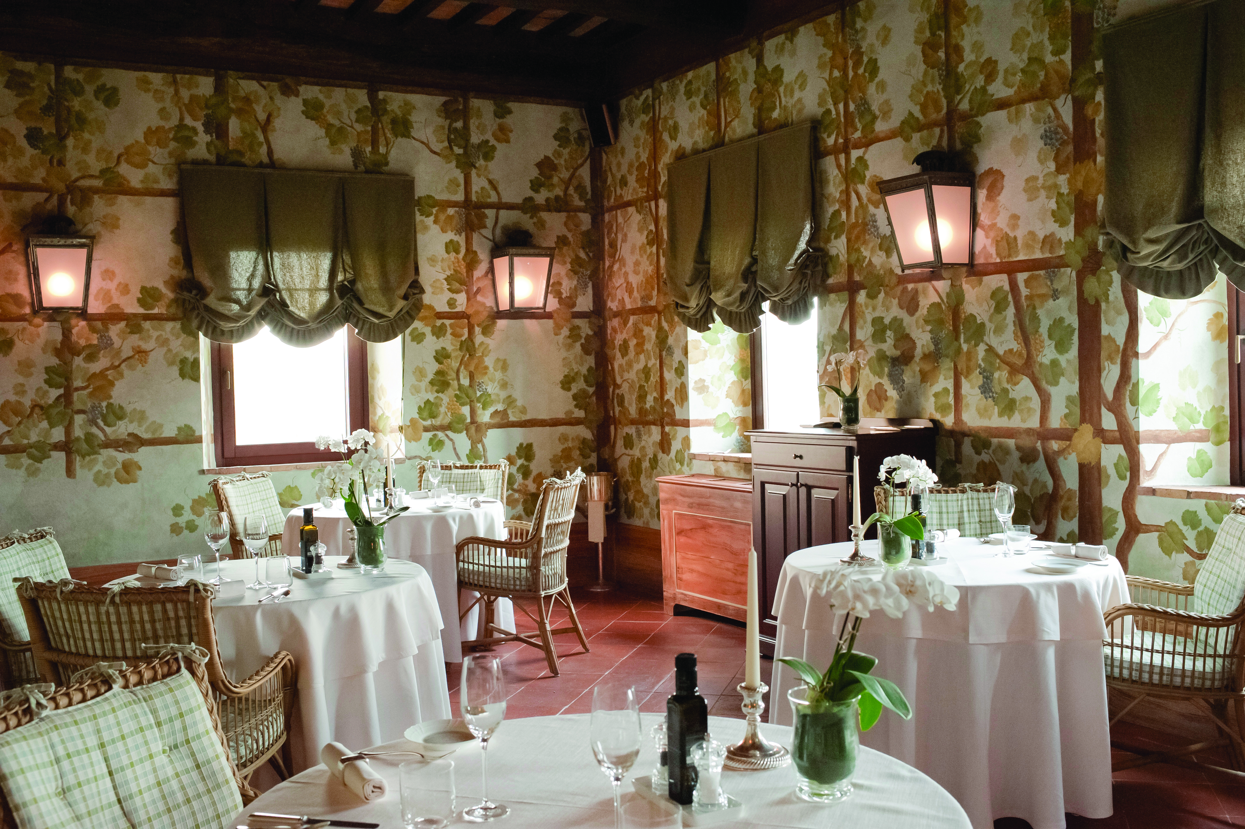 Castello banfi il borgo restaurant called the Sala dei Grappoli with circular tables set up around the room with pink table cloths 