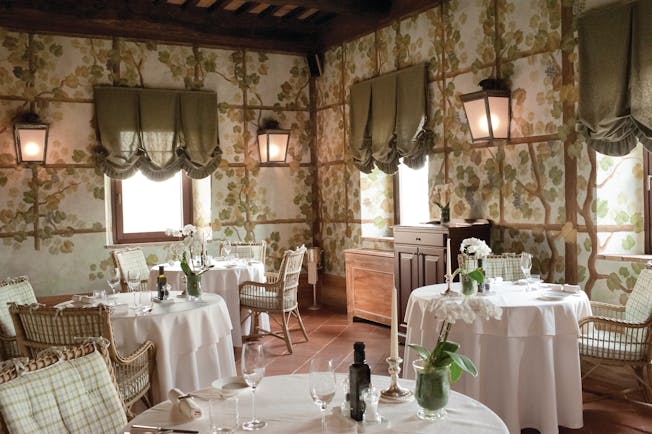 Castello banfi il borgo restaurant called the Sala dei Grappoli with circular tables set up around the room with pink table cloths 