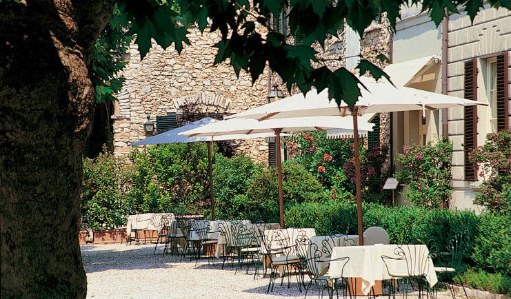 Grotta Giusti Tuscany patio outdoor dining area tables chairs umbrellas trees