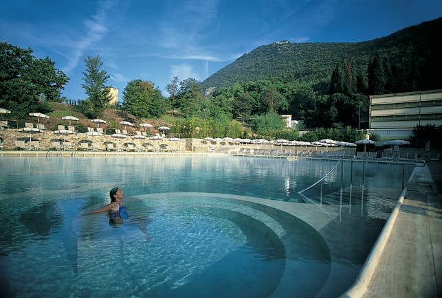 Grotta Giusti Tuscany pool sun loungers umbrellas woman in hydro massage area 