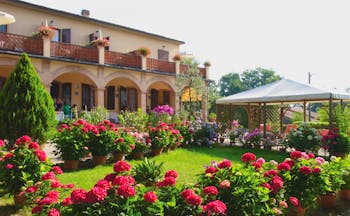 Hotel Le Renaie Tuscany lawns potted plants pink flowers hotel building in background