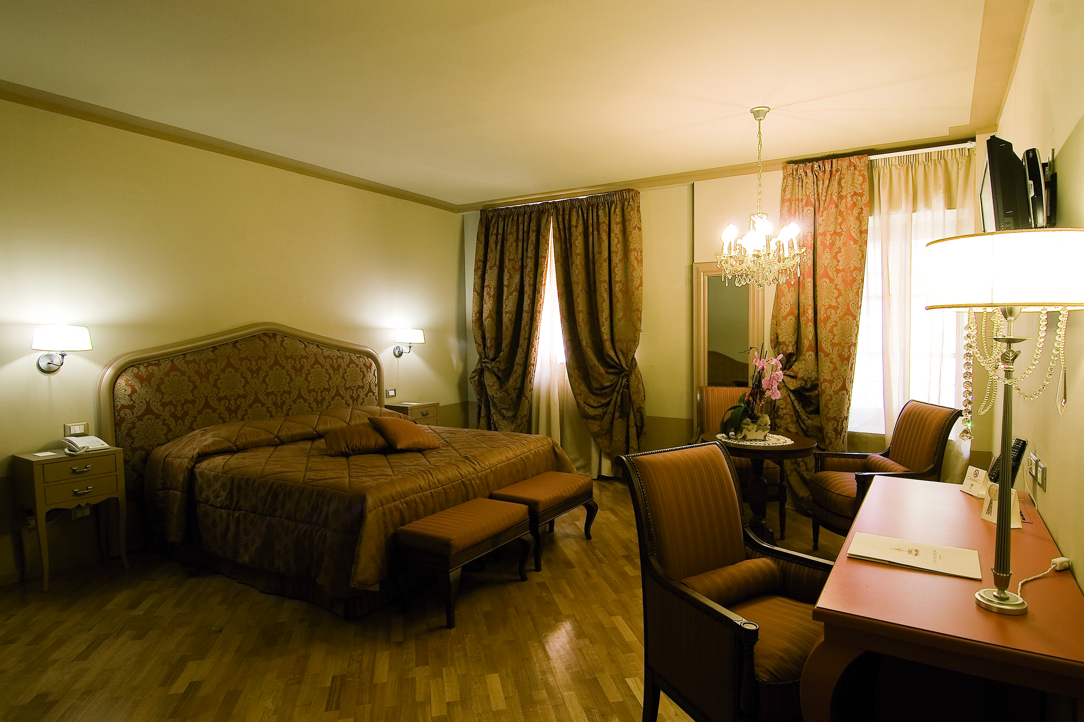 Bedroom with chandelier, brown and beige colour scheme and draping curtains