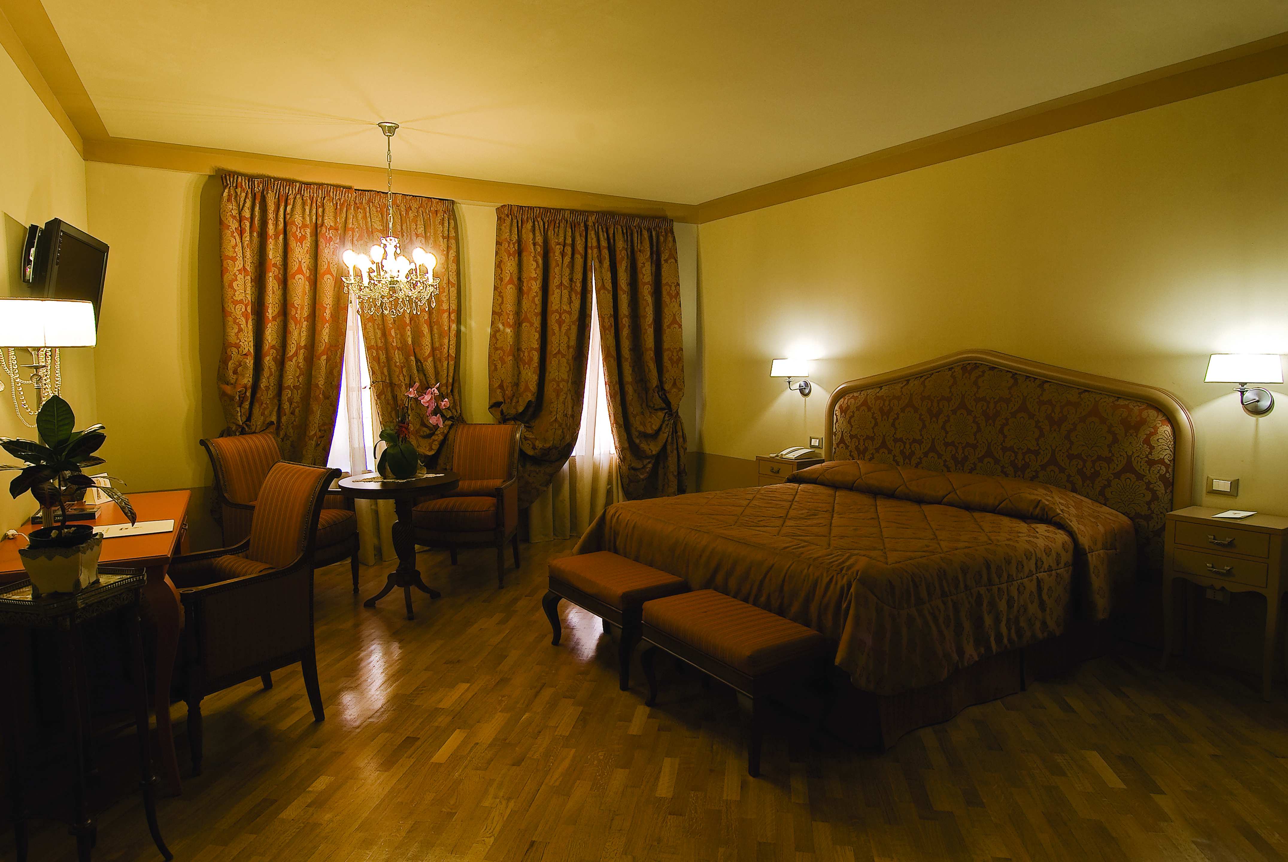 Double room at the Hotel San Luca Palace with brown and beige colour scheme, large double bed, chandelier and draping curtains