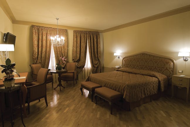 Double room at the Hotel San Luca Palace with brown and beige colour scheme, large double bed, chandelier and draping curtains